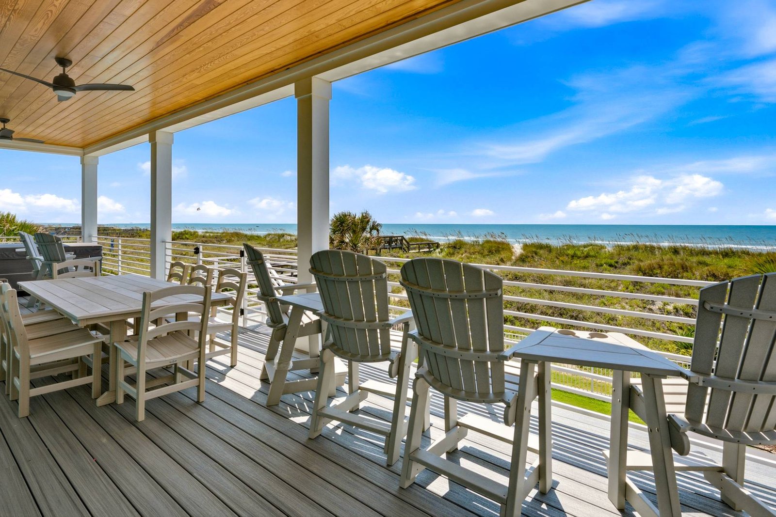 Covered oceanfront deck with dining and Adirondack seating